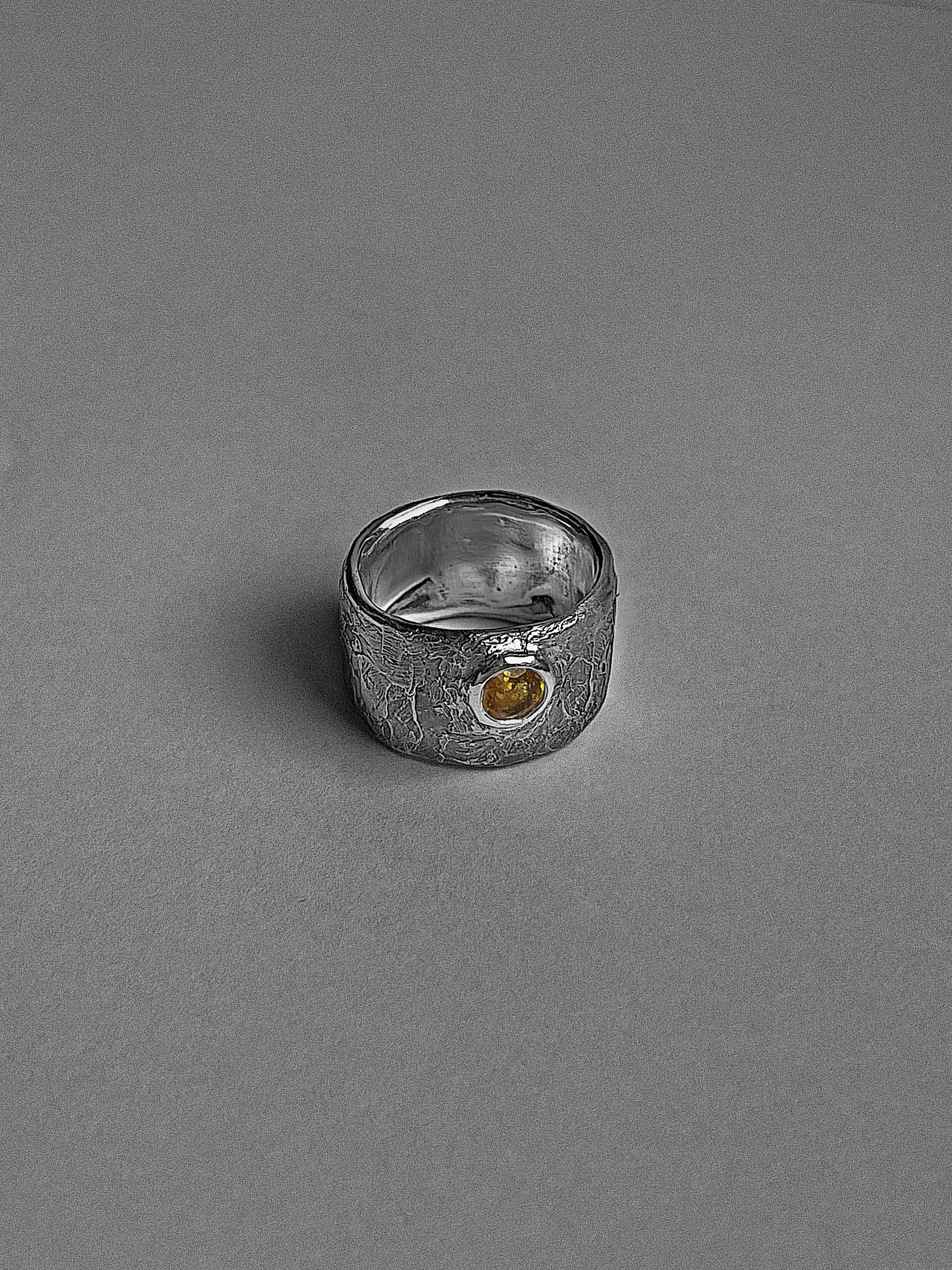 Silver ring with a yellow gemstone on a gray background