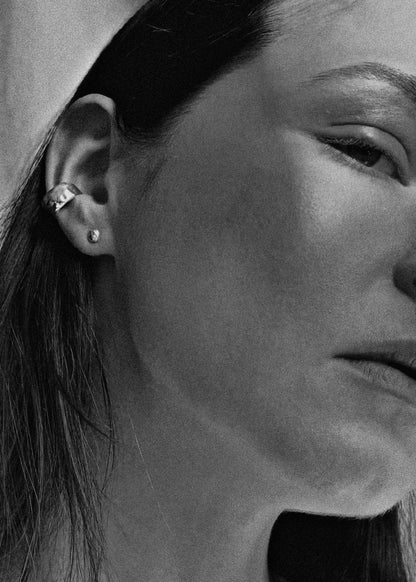 Close-up of a person wearing an earring with a neutral background